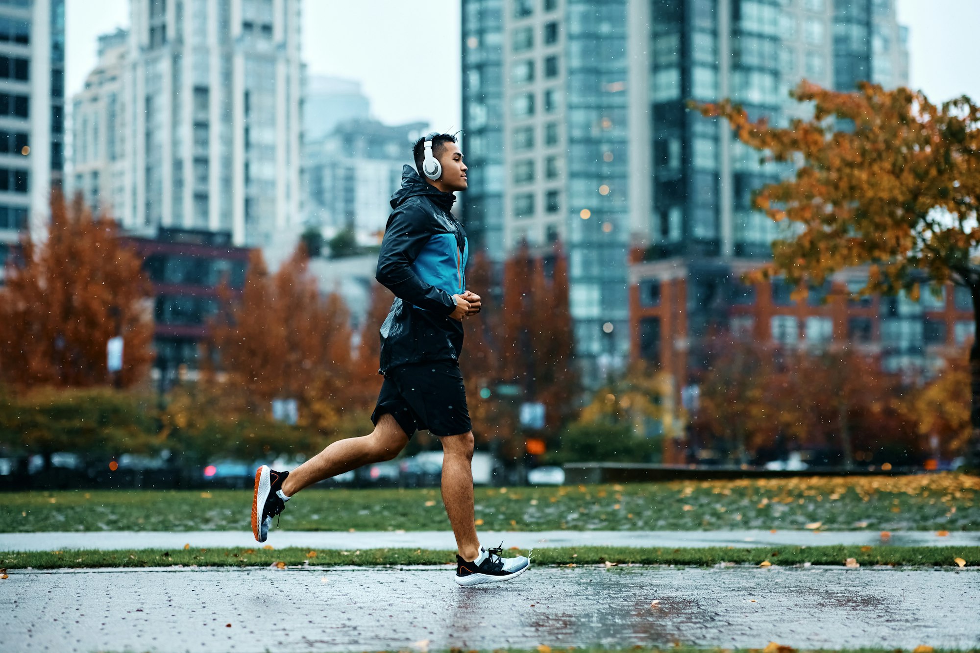 Side view of sportsman running while exercising in the park during rainy day.